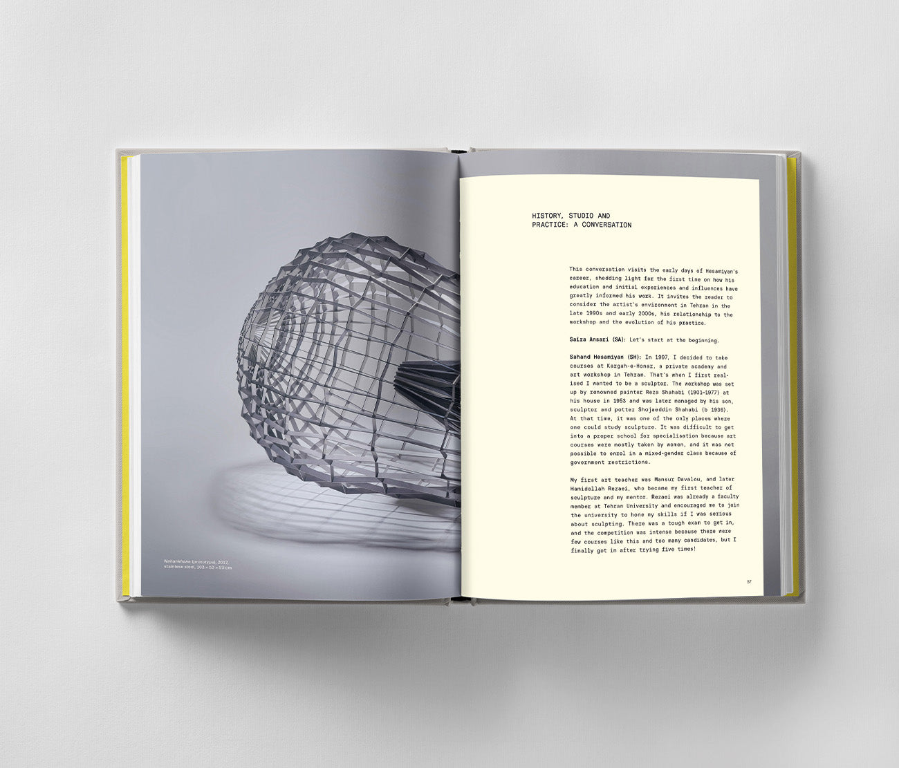 A wire sculpture resembling Sahand Hesamiyan's work is displayed on the left page of an open book, titled "Sahand Hesamiyan: Primary Structures" by Black Dog Online. It draws inspiration from Islamic and Persian architecture, with text on the right against a pristine white background.