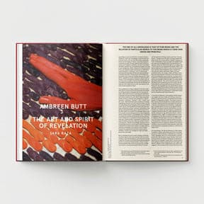 An open book features an art piece on one page and text on the other. The artwork showcases an orange hand with abstract designs, reminiscent of Indo-Persian miniature painting, titled "What Comes to My Lips" by Ambreen Butt from Black Dog Online.