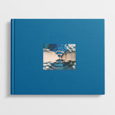 The book "Bex Day: Petal" by Black Dog Online features a blue cover with a central photograph of legs in water adorned in blue clothing. The title "PETAL" and author "BEX DAY" are subtly embossed in blue on the cover, challenging taboos through its evocative imagery and underlying themes.