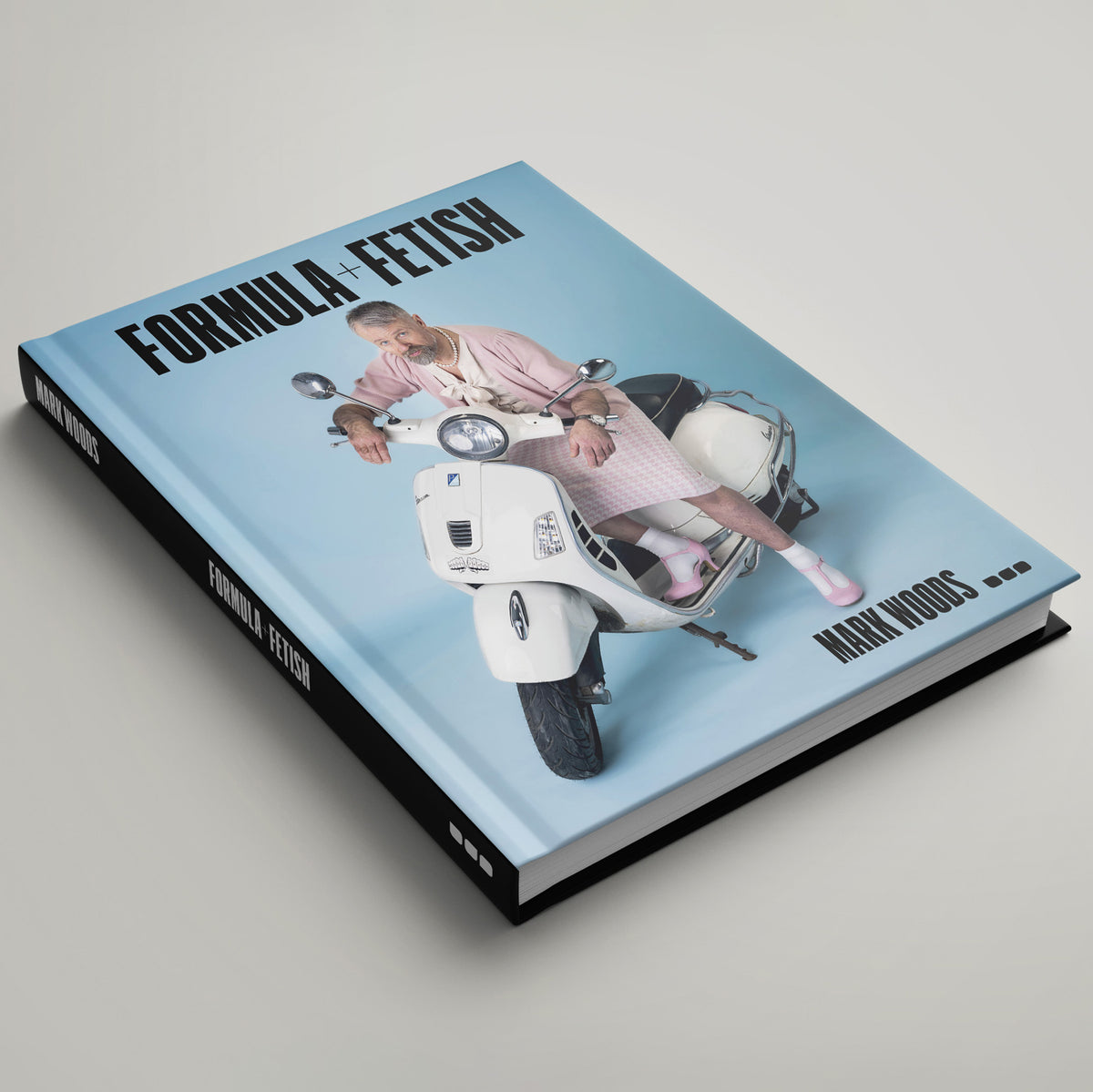 Formula + Fetish" is a hardcover book by Black Dog Press featuring an older woman in pink, adorned with jewellery and fine art elements, seated on a white scooter against a blue background.