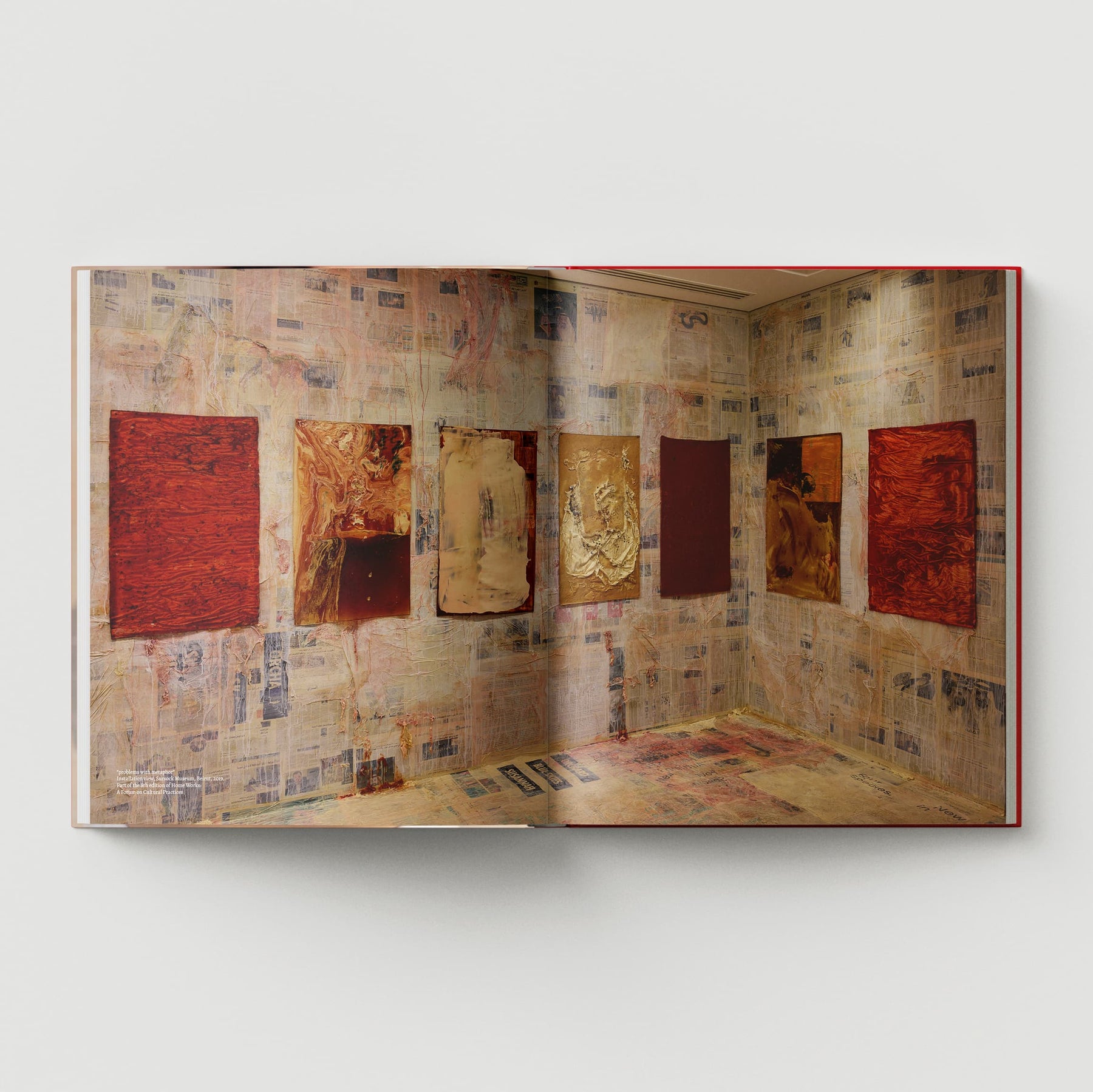 The book titled "The Makeshift Body: Mandy El-Sayegh" by Black Dog Online reveals pages featuring abstract art on walls draped in newspaper, capturing the evocative style of contemporary artist Mandy El-Sayegh.