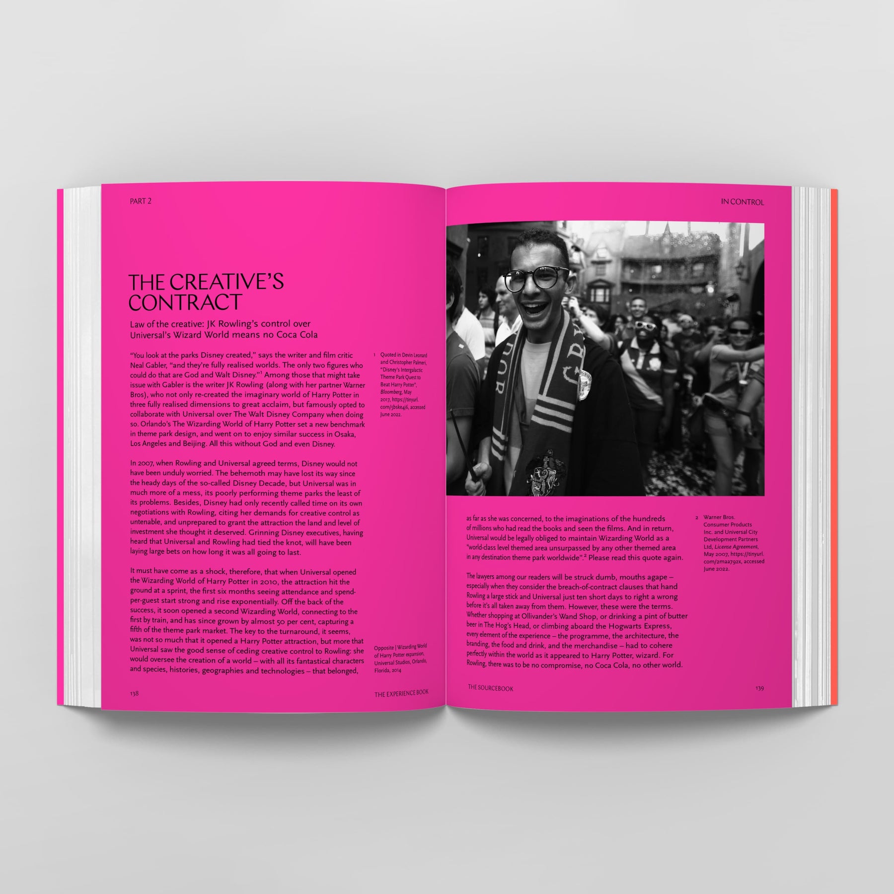 An open book with pink pages shows two columns of text on each page. The left page is titled "The Creative's Contract." The right page, reminiscent of "The Experience Book: For Designers, Thinkers & Makers" by Black Dog Online, features a black-and-white photo of people at an outdoor event, capturing the essence for experience designers to draw insights from.