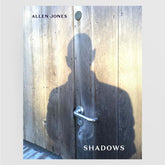 A person's shadow falls on a wooden door with a metal handle; "Black Dog Online" is at the top left and "Shadows" at the bottom right, reflecting imagery from the Black Dog Online art book, *Shadows*.