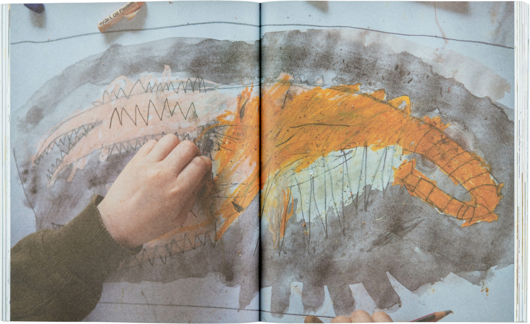 A child busily works on a vibrant abstract creature with pastels, exploring mark-making abilities using striking orange and black hues and jagged lines, reminiscent of a creative activity from "Drawing Projects for Children" by Black Dog Online.