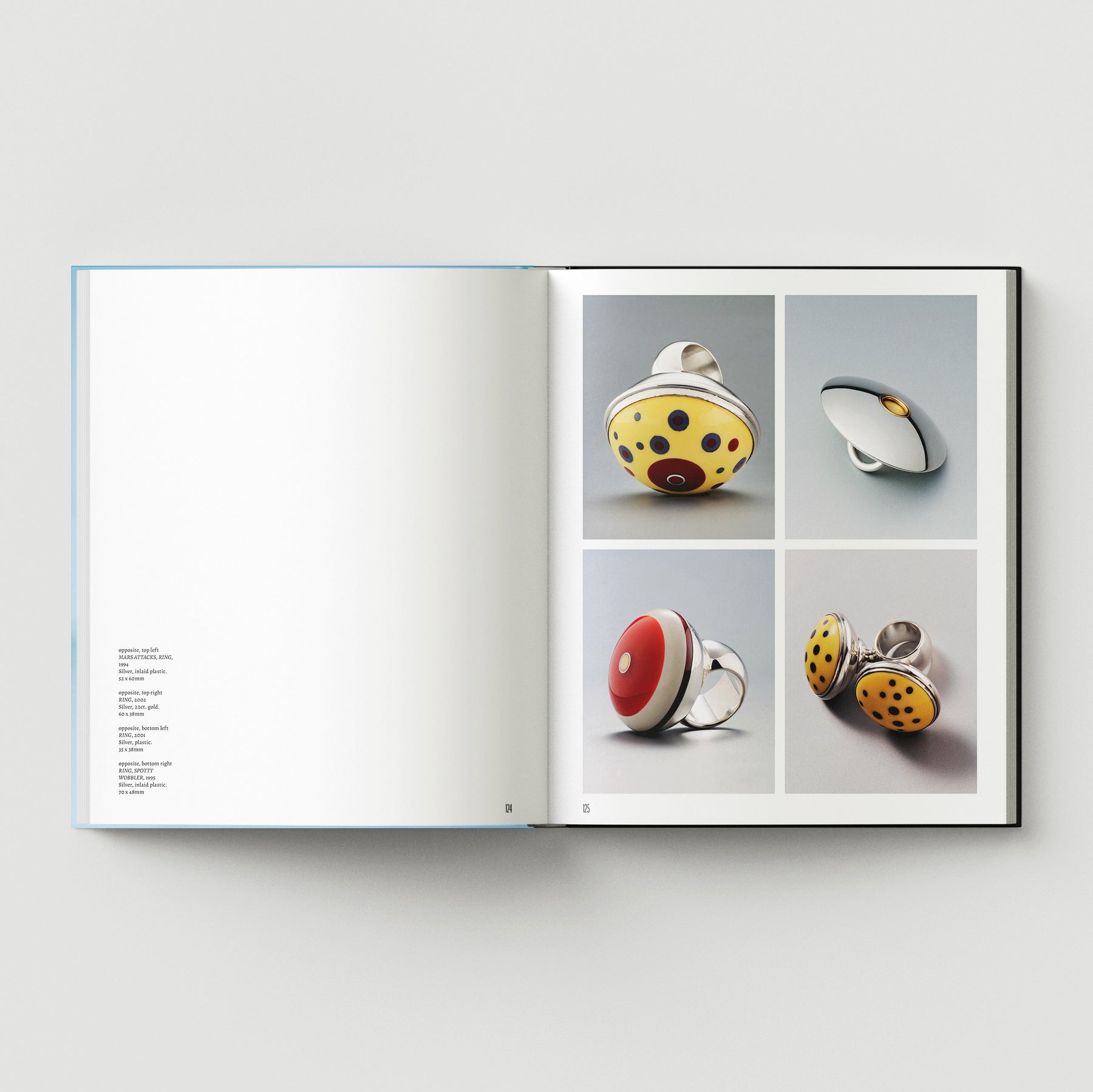 An open book, "Formula + Fetish" by Black Dog Press, displays four photos of modern circular rings—bold colors and patterns on the right page, with minimal left-page text—blending jewellery with fine art.