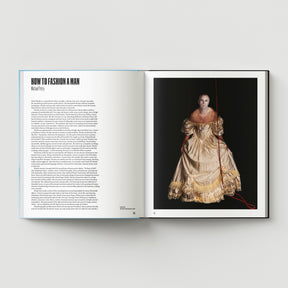 An open book, "Formula + Fetish" by Black Dog Press, shows an article titled "How to Fashion a Man" on the left page and a photo of jewellery and art by British artist Mark Woods—an ornate gold dress with red strings—on the right.