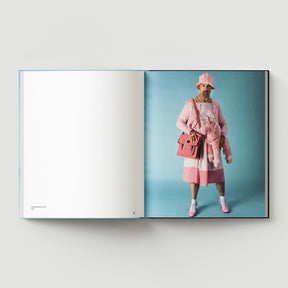 British artist Mark Woods appears in pink clothing with a pink bag and stuffed animal, set against a light blue backdrop, on the right page of "Formula + Fetish" by Black Dog Press.