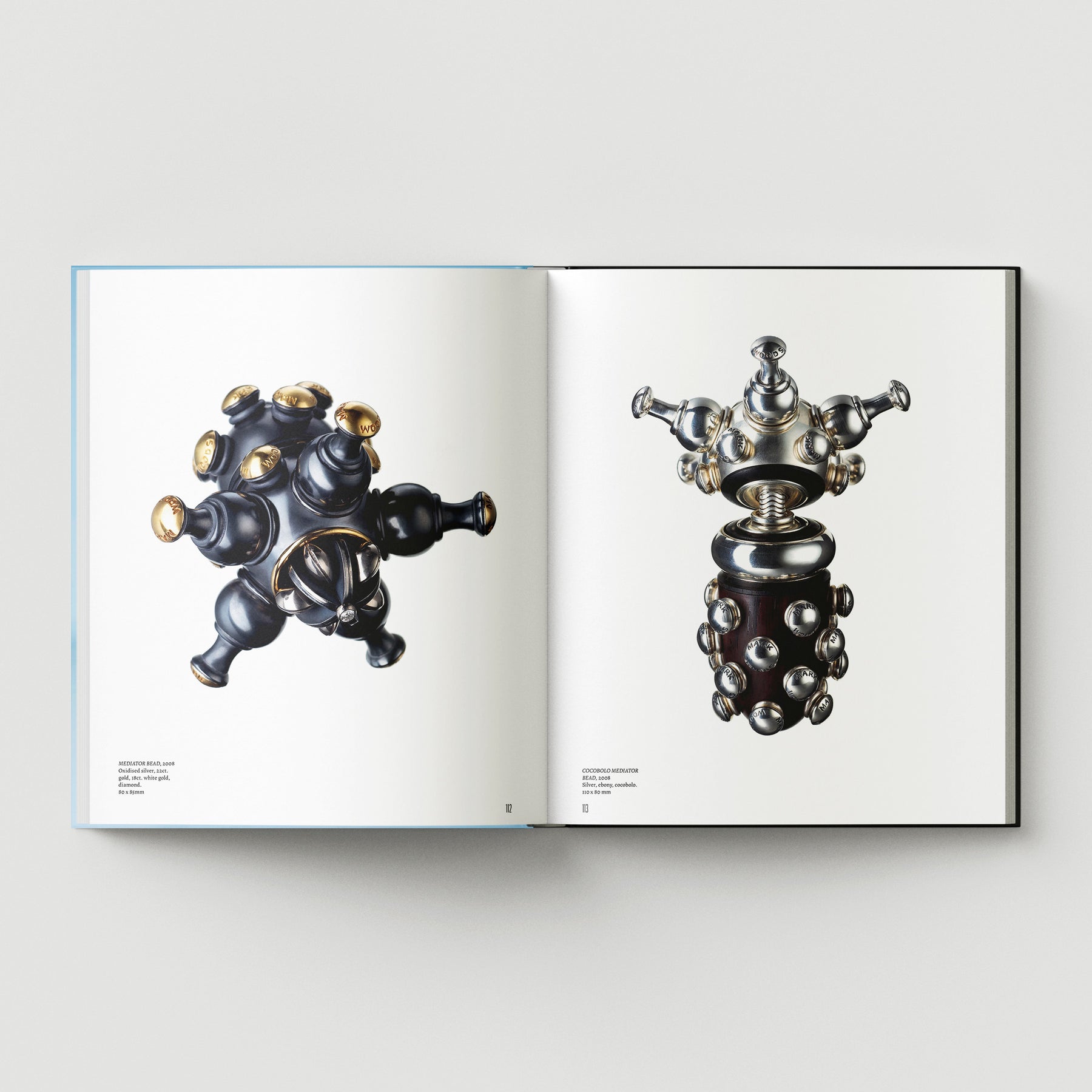 An open book titled "Formula + Fetish" by Black Dog Press shows two pages with images of metallic, abstract, symmetrical sculptures merging jewellery and fine art against a white background.