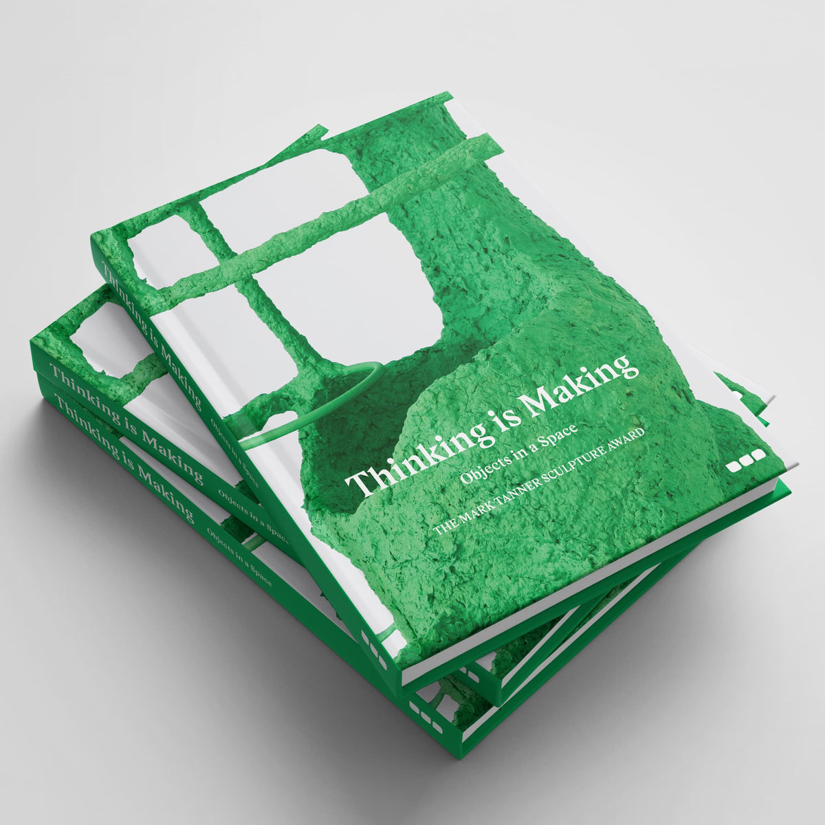 A stack of books titled "Thinking is Making: Objects in Space The Mark Tanner Sculpture Award," featuring a green and white abstract cover design, delves into contemporary sculptural practice, making it an essential read for emerging sculptors. Published by Black Dog Online.